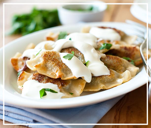 Zdjęcie pierogi z okrasą śmietany - tradyjna polska kuchnia. Photo of Polish pierogi with cream topping - traditional Polish Cuisine